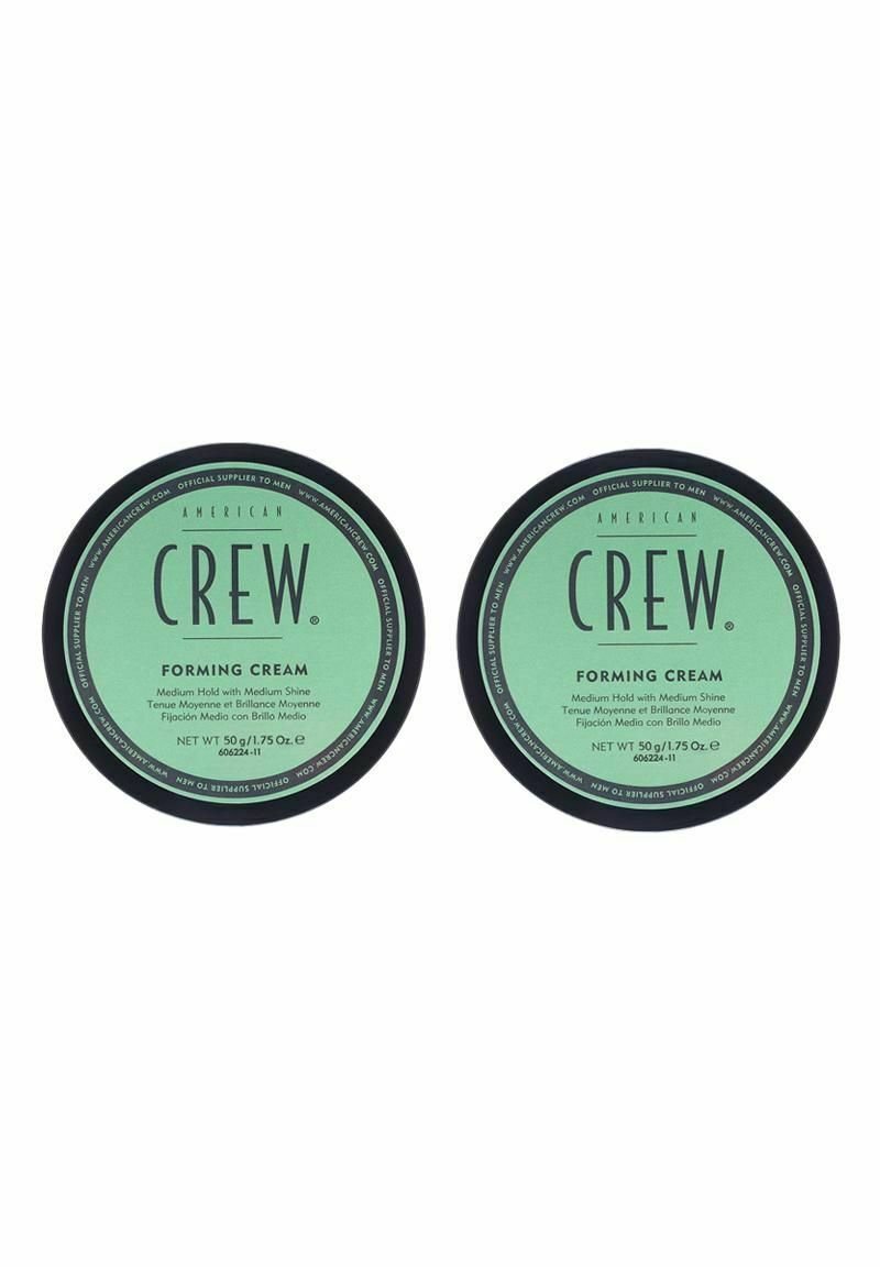 Två runda burkar med American Crew stylingkräm. Gröna etiketter med svart text som anger medelhårt grepp och glans, 50g vardera, slät finish.