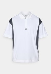 Kortermet polo skjorte i hvit med grå sidestykker, glidelås krage og logo på brystet. Laget av pustende stoff, avslappet passform.