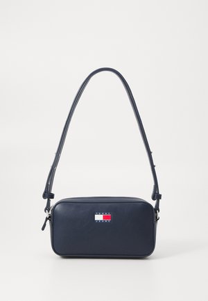 Bolso cruzado en color marino, hecho de piel sintética, diseño rectangular, correa ajustable, con parche de logo en colores rojo, blanco y azul.
