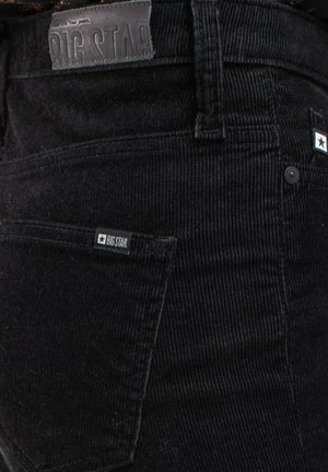 Czarne spodnie sztruksowe o fakturowanym wykończeniu, z skórzaną łatą oznaczoną napisem "BIG STAR" oraz małymi metkami z logo na kieszeniach.