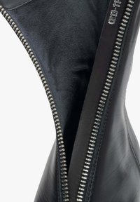 Black leather ankle boot with a silver zipper detail, featuring a smooth surface, sleek shape, and a contrasting interior material.