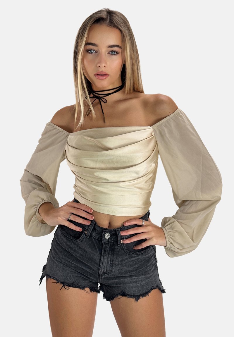 Beige Schulterfreies Oberteil mit Stoffüberlagerung und voluminösen Ärmeln, kombiniert mit ausgefransten schwarzen Denim-Shorts. Dünnes schwarzes Choker-Accessoire.