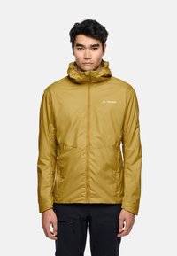 Yellowish-brown lightweight jacket with a hood, zipper front, two side pockets, and a logo on the chest. Smooth, water-resistant fabric.