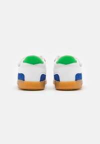 Baskets en cuir blanc avec des panneaux en daim bleu et des accents verts, disposant d'une semelle en caoutchouc gomme et d'un design arrière arrondi.