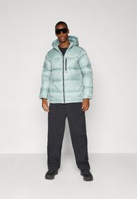 Light blue puffer jacket with a hood, front zipper, and black accents; paired with dark cargo pants and black shoes.