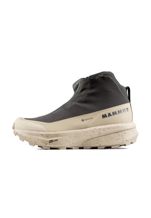 Zwart-beige hoge wandelschoen met gestructureerde zool, Gore-Tex-label, Mammut-merk en trekbandje aan de hielzijde.