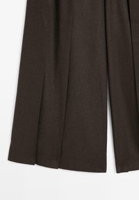 Wijde pijpen broek in donkerbruine stof, met een zachte textuur en diepe plooien, afgewerkt met een nette zoom voor een gestructureerde uitstraling.