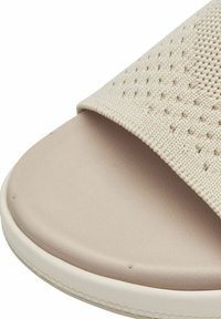 Beige slip-on szandál texturált szövetpánttal és sima, strapabíró talppal. A dizájn perforált részletekkel rendelkezik a pánton.