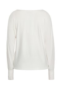 Top crem cu mâneci lungi și croială lejeră; manșete ribbate; textură moale; decolteu larg; culoare solidă; fără modele sau embellishments.