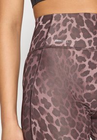 Κολάν με λεοπάρ μοτίβο σε αποχρώσεις μαβί και καφέ, με ψηλή μέση και την επιγραφή "DRYCELL" στη μπροστινή ραφή. Μαλακό, ελαστικό ύφασμα.