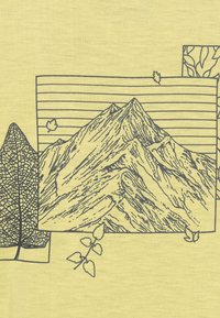 Tessuto giallo con un'illustrazione di montagna caratterizzata da linee dettagliate, incorniciata da un motivo a foglie e strisce orizzontali sullo sfondo.