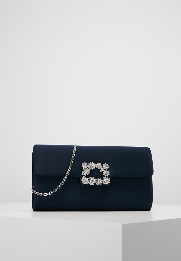 Námorně modrá psaníčko vyrobené z hladké tkaniny, se stříbrným řetízkem a květinovou ozdobou z kamínků na přední straně.