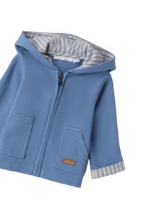 Felpa con zip blu realizzata in tessuto testurizzato, con due tasche frontali e una fodera beige a righe all'interno del cappuccio. Piccola toppa con logo sulla tasca.