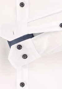 Weißes Hemd mit blauen strukturierten Akzenten, schwarzen Knöpfen und einem einzigartigen Manschettendesign mit Knopfverschlüssen.