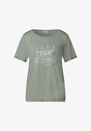 T-shirt verde a maniche corte con scollatura rotonda, caratterizzato da testo bianco in vari font e stili, e un dettaglio di orlo arricciato nella parte inferiore.
