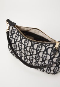 Borsa a spalla a motivi bianco e nero realizzata in tessuto testurizzato, con chiusura a zip, fodera interna beige e tracolla in pelle nera.