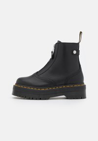 Black leather ankle boots with a zip closure, textured platform sole, and contrasting yellow stitching along the edge.