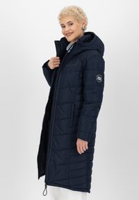 Navyblauwe gewatteerde jas met een capuchon, gestikte patroon, ritssluiting, verstelbare trekkoord en een logobadge op de mouw.