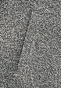 Tessuto grigio strutturato con fibre strettamente arricciate, che creano una superficie morbida e pelosa. Il design presenta un aspetto a strati con dimensioni di anelli variabili.