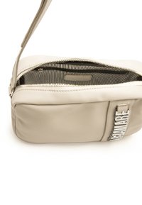 Bolso de mano de cuero beige con cierre de cremallera, forro interior a rayas y un detalle metálico en el lateral. Forma rectangular compacta.