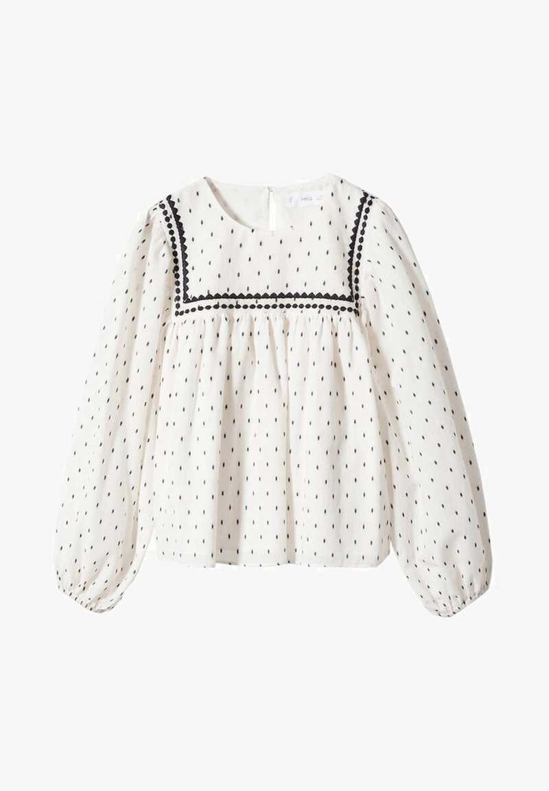 Blouse blanche à manches longues avec petits pois noirs, empiècement carré orné d'un bord festonné et pointillé noir, taille froncée et poignets élastiques.