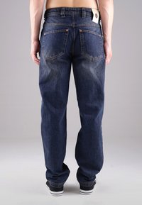 Dunkelblaue Jeans aus Denim mit entspannter Passform, ausgestattet mit Gesäßtaschen, Kupferriegeln und einem Etikett am Bund. Maschinenbearbeitete Textur.