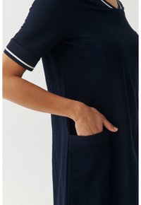 Robe bleu marine en tissu doux, avec des manches courtes ornées de rayures blanches, une poche sur le côté et une coupe décontractée.