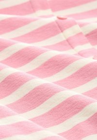 Tejido a rayas en rosa y blanco con una superficie texturizada. Las rayas son onduladas y se puede ver un pequeño botón rosa.