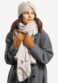 Hellgrauer Wollmantel, cremefarbener Fransen-Schal, braune Lederhandschuhe und ein beigefarbener gestrickter Haarband, die einen texturierten und geschichteten Look zeigen.