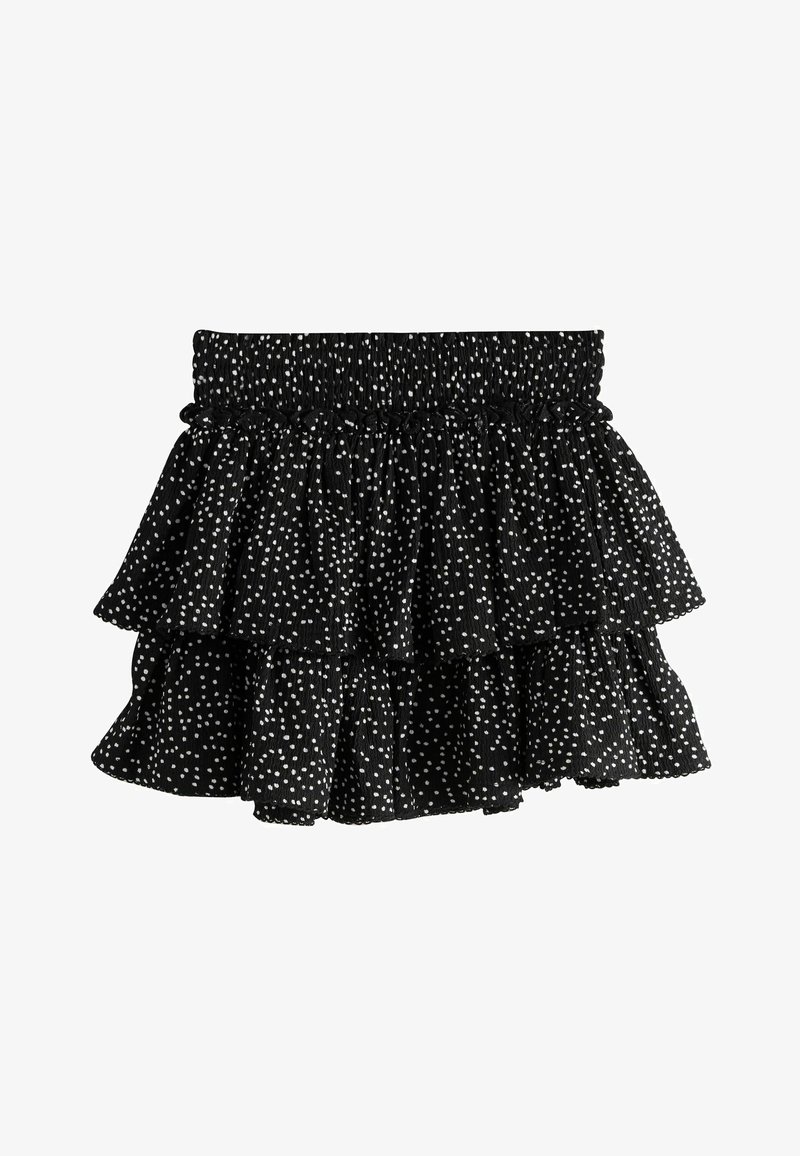 Mini-jupe noire à volants avec pois blancs irréguliers et taille élastique froncée.