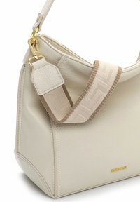 Borsa a mano in pelle color crema con finitura testurizzata. Presenta una tracolla larga e decorata e ferrature dorate. Contiene dettagli accentuati geometrici.