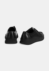 Schwarze Ledersneaker mit glatter Oberfläche, runder Zehenpartie und flexibler Gummisohle. Ausgestattet mit Schnürsenkeln und einem gepolsterten Schaft für zusätzlichen Komfort.