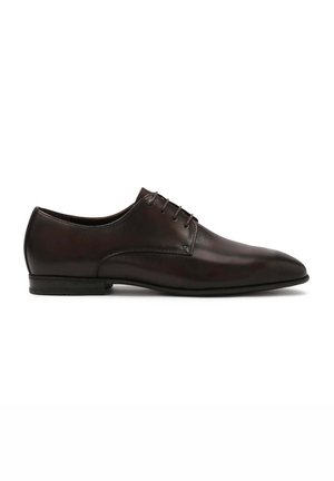 Zapato de vestir de cuero marrón con un diseño elegante, puntera puntiaguda y cinco ojetes. Textura suave con costuras mínimas y suela negra baja.