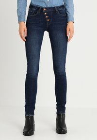 Smala jeans i mörkblå denim, med en femknapps-stängning, klassiska fickor och ett mjukt, strukturerat tyg.