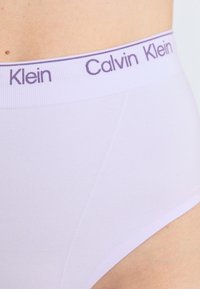 Lilac underwear with a soft texture, featuring a wide elastic waistband labeled "Calvin Klein" in purple lettering.
