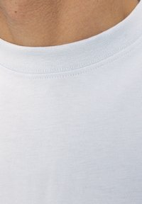 Vaaleansininen puuvillapaita, jossa on pyöreä kaula-aukko ja kierretty viimeistely. Kankaan pinta näyttää sileältä ja siinä on pehmeä tekstuuri.