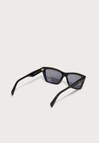 Occhiali da sole neri a forma di occhio di gatto con lenti scure, montatura in plastica elegante e design angolare. Presentano sottili accenti dorati sulle aste.
