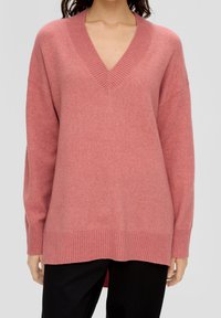 Pull en tricot rose rosé avec un col en V, des poignets et un ourlet côtelés, doté d'une coupe détendue et d'un dos plus long. Texture lisse et matière douce.
