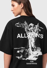 T-shirt in cotone nero con una grande grafica di un angelo circondato da nuvole, con il testo "ALLSAINTS LONDON" sopra e "THE SAINTHOOD" sotto.