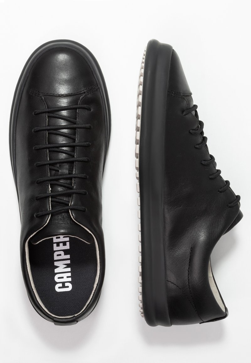 Schwarze Leder-Sneaker mit runder Spitze, minimalistisches Design, Schnürverschluss und weiße Gummisohle mit gemustertem Rand.