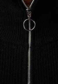 Zwarte gebreide trui met ritssluiting, voorzien van een zilverkleurige metalen rits met een ronde trekker, met een gestructureerde stof.