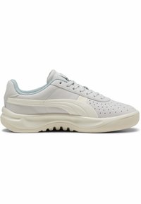 Zapatilla de cuero blanca con parte superior perforada, acentos en azul claro, cordones redondos y una suela gruesa en color crema con un patrón de agarre texturizado.