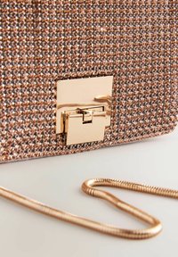 Rózsaarany színű clutch, amelynek texturált felülete apró, fényes kristályokkal van borítva. Fém csattal és vékony, fém lánc pánttal rendelkezik.