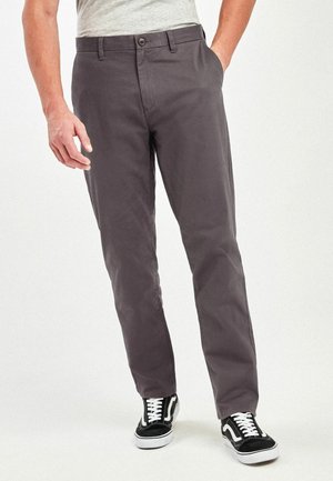 Grå bomulds chinos med lige ben, forlommer, knaplukning og parret med sort-hvide sneakers.
