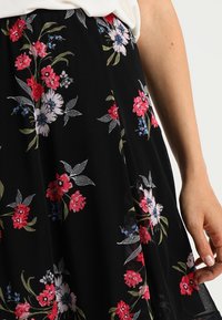 Černá květinová sukně s mixem červených, růžových a modrých květin, se zelenými listy; jemná tkanina a splývavý střih, sukně částečně délce.