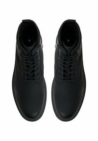 Zapatos de cordones negros con una parte superior de cuero liso, punta redonda, collar acolchado y acento de metal. La suela es ligeramente texturizada.