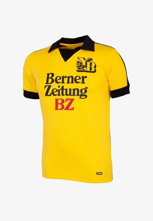 Geel voetbalshirt met korte mouwen, voorzien van een zwarte kraag en manchetten, met het logo "Berner Zeitung BZ" in zwarte tekst op de voorkant.