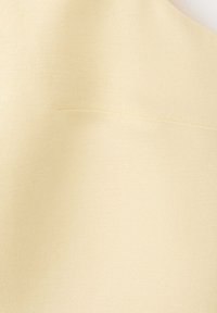 Tissu de couleur crème avec une texture subtile, montrant une couture horizontale et des plis doux.