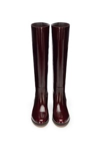 Bordowe skórzane kozaki sięgające kolan, z połyskującym wykończeniem, zaokrąglonym noskiem i gładką teksturą, z minimalnym przeszyciem i bez widocznych elementów metalowych.