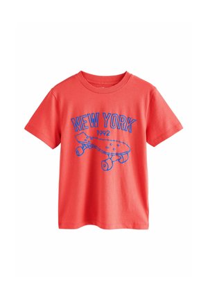 Kortärmad, korallfärgad bomullströja med blå tryckt text "NEW YORK" och en skateboarddesign med hjul och prickar.